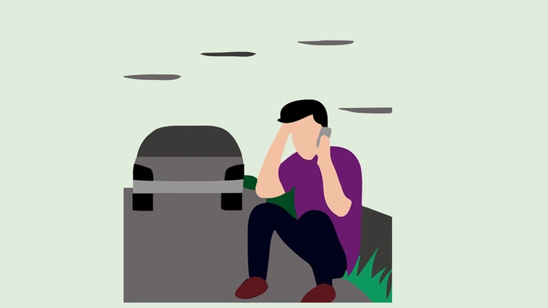 A man sitting on the road and talking on his mobile phone following a car accident