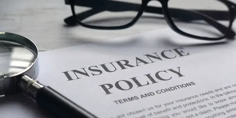 A personal accident insurance policy document on a desk next to a magnifying glass and eye glasses.